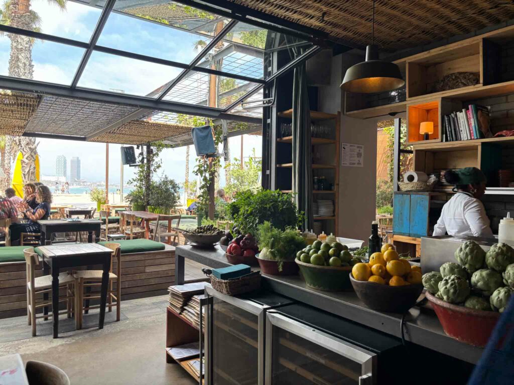 Fresh produce on an interior bench and a view of the beach in the background at Gallito restaurant in Barcelona