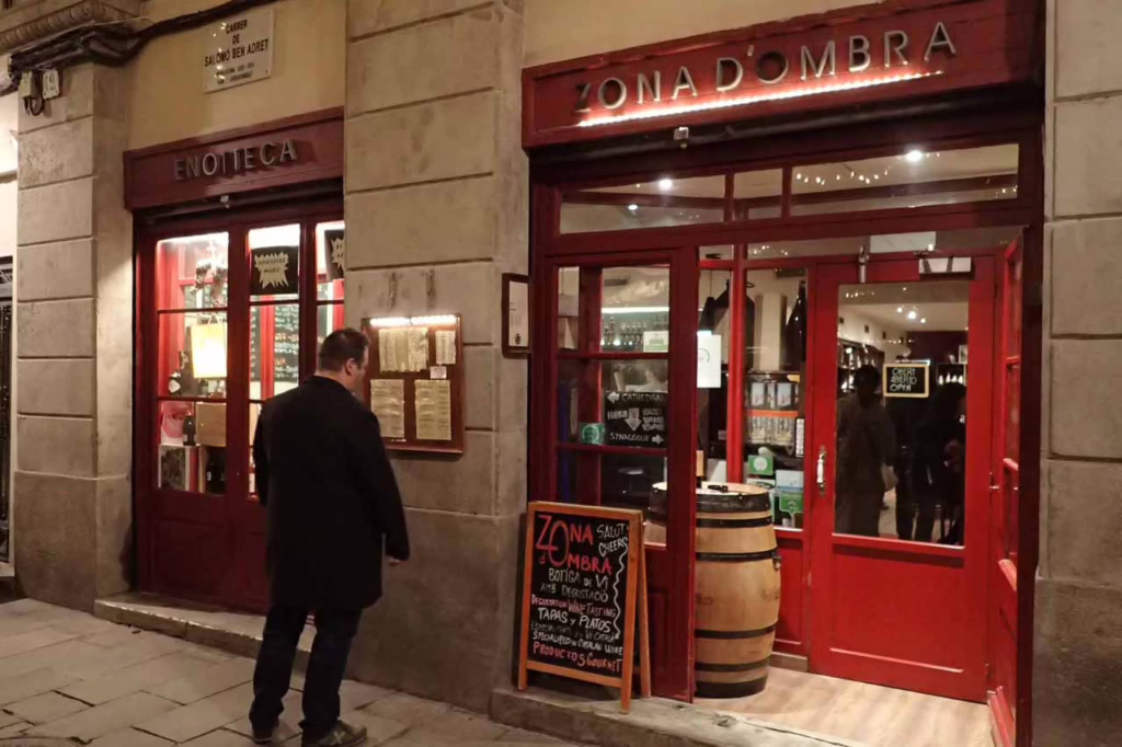 Exterior of Zona d'umbra wine bar in barcelona with a customer reading a chalkboard